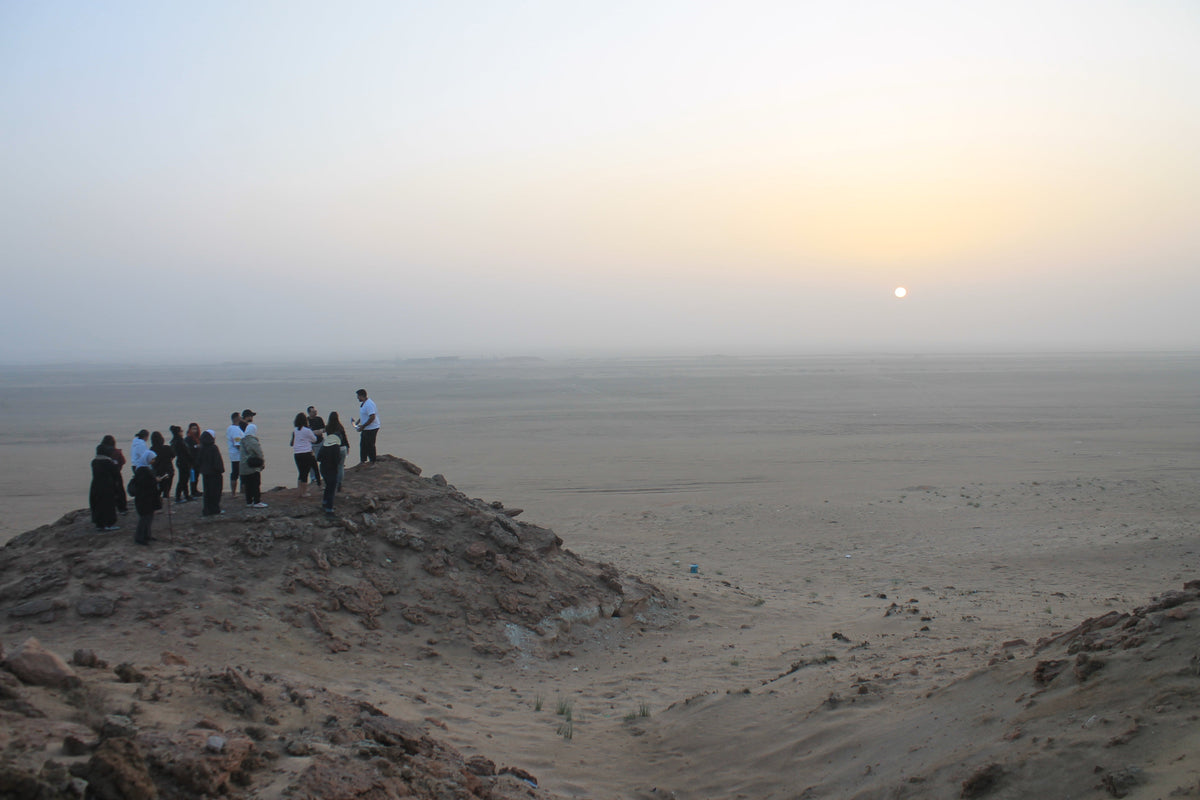 AlMaknoon explorers overlooking Kuwait's desert landscape at sunset